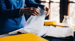 Επαγγελματίας τυλίγει γυάλινο βάζο με bubble wrap για συσκευασία εύθραυστων αντικειμένων με ασφάλεια Prime