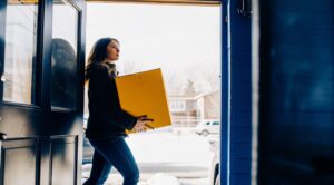 Young Prime woman carrying moving boxes, applying moving guide for individual moving successfully
