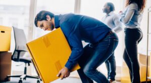 Επιχειρηματίας της Prime εφαρμόζει σωστή ανύψωση αντικειμένων, εστιάζοντας στη μετακόμιση βαρέων αντικειμένων στο γραφείο